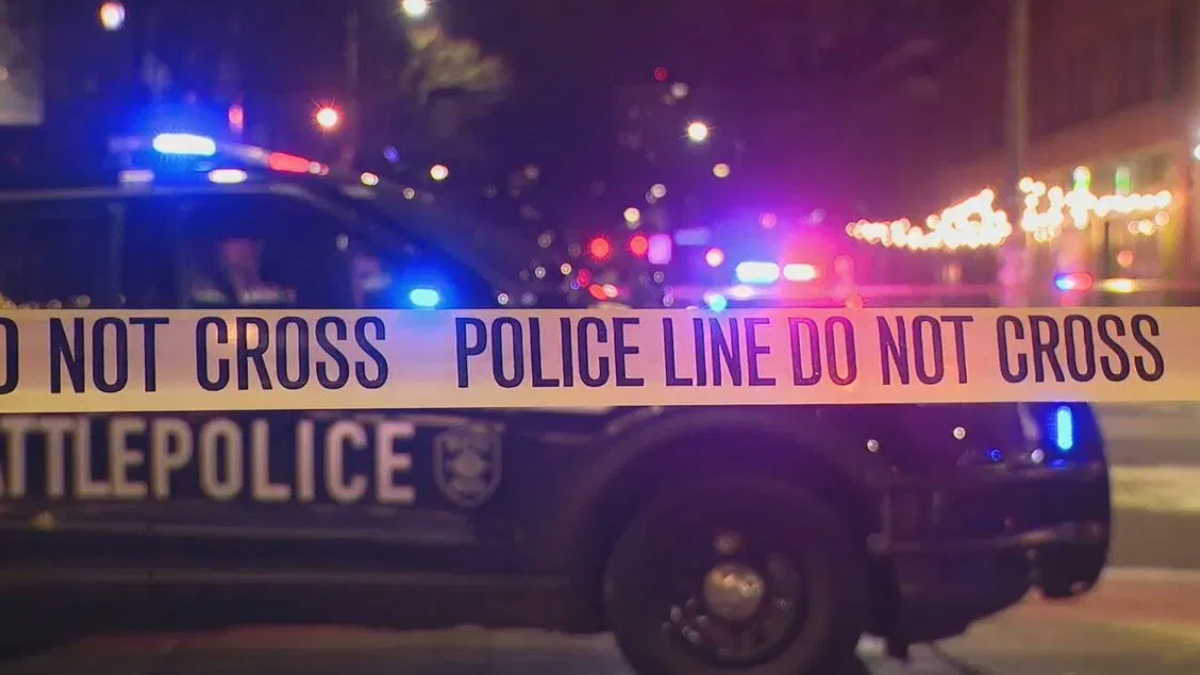 Nighttime street scene with police car and 'Do Not Cross' barrier tape, police lights flashing in the background.