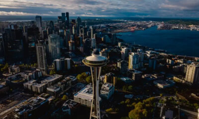Aerial view of downtown Seattle with the Space Needle rising among skyscrapers and Puget Sound beyond.