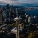 Aerial view of downtown Seattle with the Space Needle rising among skyscrapers and Puget Sound beyond.