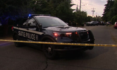 Seattle Police SUV with blue lights on a residential street behind yellow crime tape
