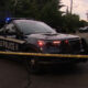 Seattle Police SUV with blue lights on a residential street behind yellow crime tape