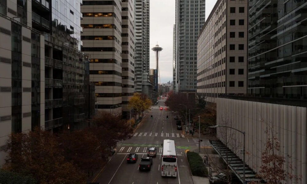 Downtown street with high-rise buildings on both sides and the Space Needle visible in the distance.