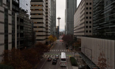 Downtown street with high-rise buildings on both sides and the Space Needle visible in the distance.