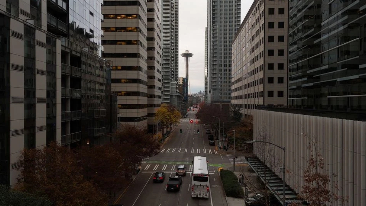 Downtown street with high-rise buildings on both sides and the Space Needle visible in the distance.