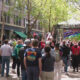Crowd of people in an urban plaza watching a large outdoor screen that says Welcome to Pioneer Square.