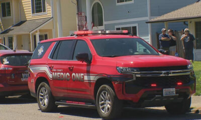 Red King County Medic One SUV parked on a residential street with flashing lights on top and people standing near a blue house in the background