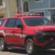 Red King County Medic One SUV parked on a residential street with flashing lights on top and people standing near a blue house in the background