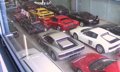 Overhead view of a showroom filled with colorful sports cars parked in rows inside a glass-walled space