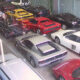 Overhead view of a showroom filled with colorful sports cars parked in rows inside a glass-walled space