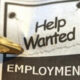 Close-up of a newspaper ad with 'Help Wanted' and 'EMPLOYMENT' visible, a gold pen pointing at it.