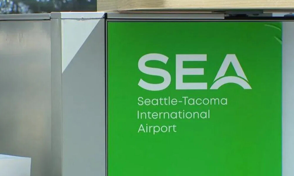 Green SEA sign for Seattle-Tacoma International Airport with stylized arch logo on white text on green background.