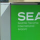 Green SEA sign for Seattle-Tacoma International Airport with stylized arch logo on white text on green background.