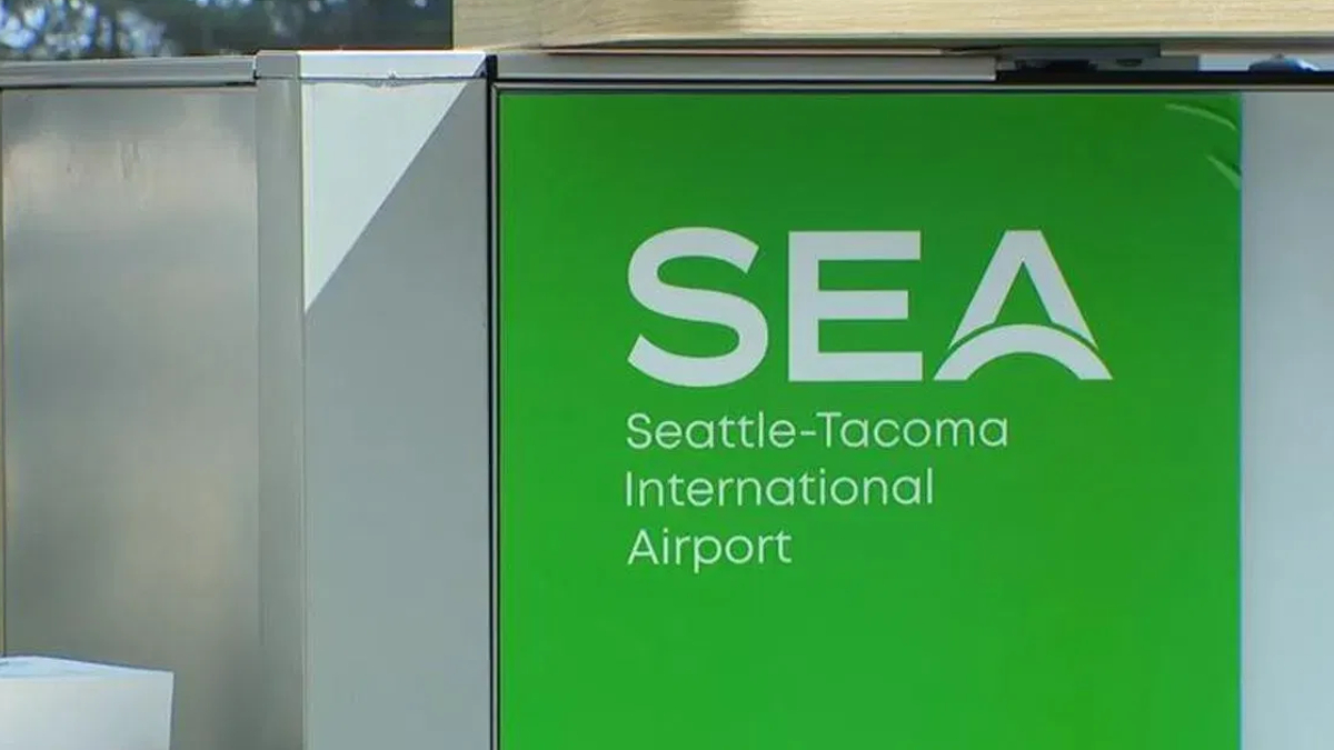 Green SEA sign for Seattle-Tacoma International Airport with stylized arch logo on white text on green background.