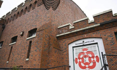 Brick exterior of the Tacoma Arts Live venue with a white door featuring a red geometric circular design.