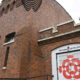 Brick exterior of the Tacoma Arts Live venue with a white door featuring a red geometric circular design.