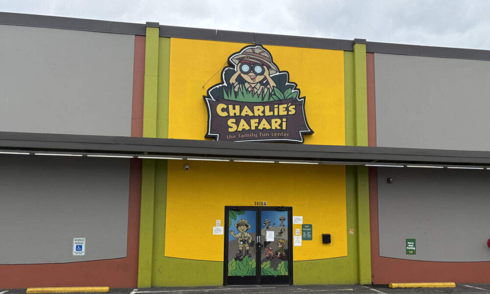 Bright yellow storefront with a large Charlie's Safari sign above the entrance and a double glass door featuring jungle cartoon characters outside a green and yellow facade