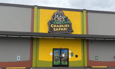 Bright yellow storefront with a large Charlie's Safari sign above the entrance and a double glass door featuring jungle cartoon characters outside a green and yellow facade