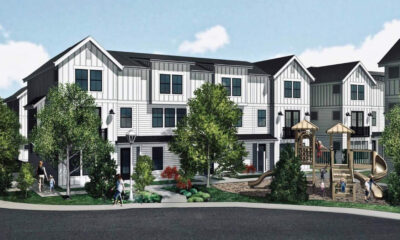 Rendering of white townhouse-style apartments with a playground and trees in a suburban complex
