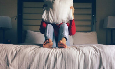 Two people on a bed, one lifting the other by the torso in a playful moment.