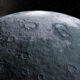Close-up view of a cratered lunar surface against a starry black space background,