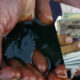Weathered hands cupping dirty water, with a triangular overlay of US currency.