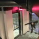 A person in a dark hoodie reaches toward the glass door at the U Wine Bar entrance, as if attempting to break in, at night outside.