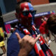 Man with red, white, and blue star face paint wearing sunglasses gives a thumbs-up at a sports event outside a stadium.