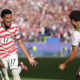 USA soccer player wearing number 17 celebrates with arms outstretched as fans cheer in a full stadium.