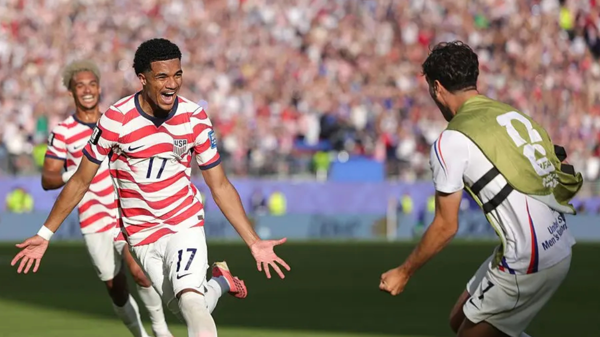 USA soccer player wearing number 17 celebrates with arms outstretched as fans cheer in a full stadium.