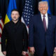 Ukrainian President Zelenskyy and former President Trump pose for a photo at a formal event with US and Ukrainian flags behind them.