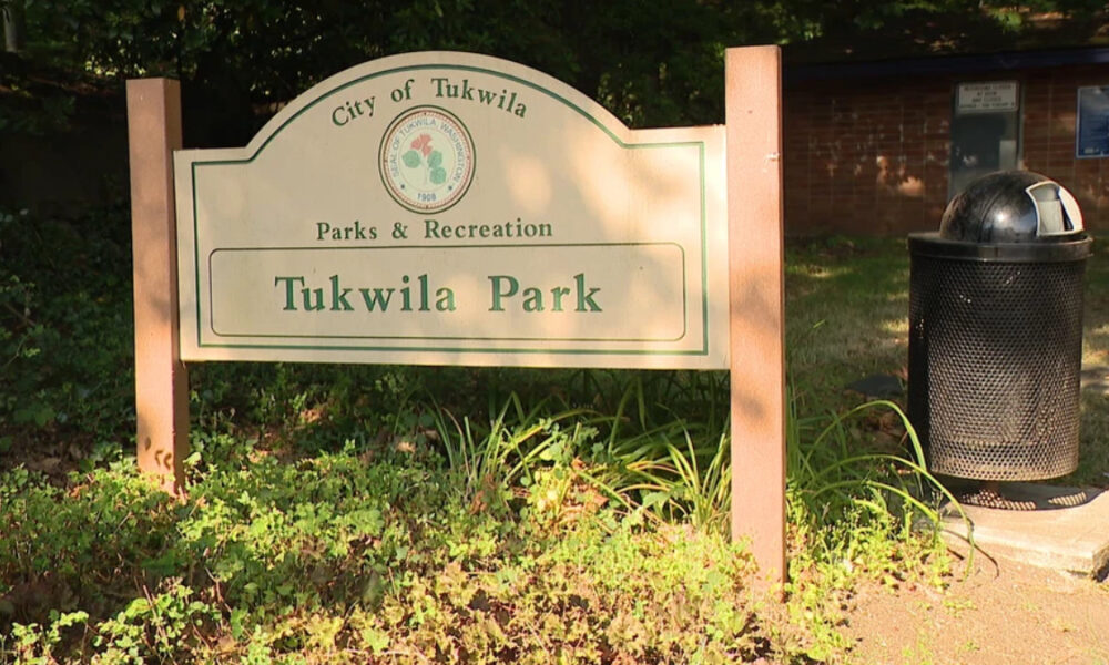 Sign reads: City of Tukwila Parks & Recreation Tukwila Park at a park entrance with greenery and a trash can nearby