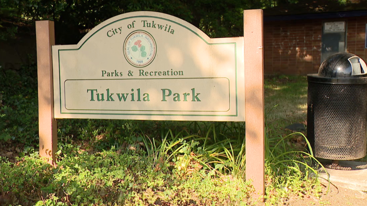Park entrance sign reading 'Tukwila Park' under Parks & Recreation, City of Tukwila, with green border and a trash can nearby.