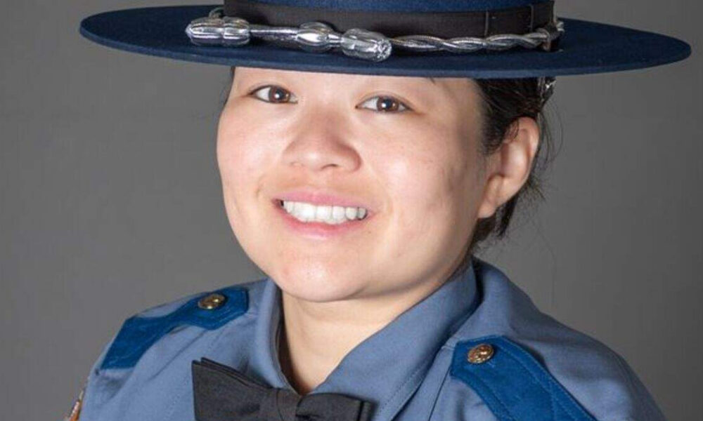 Portrait of a smiling female police officer in a blue uniform and hat.