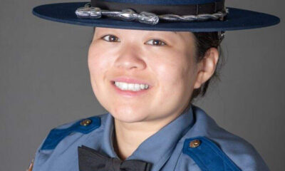 Portrait of a smiling female police officer in a blue uniform and hat.