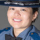 Portrait of a smiling female police officer in a blue uniform and hat.