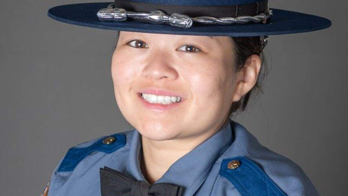 Portrait of a smiling female police officer in a blue uniform and hat.