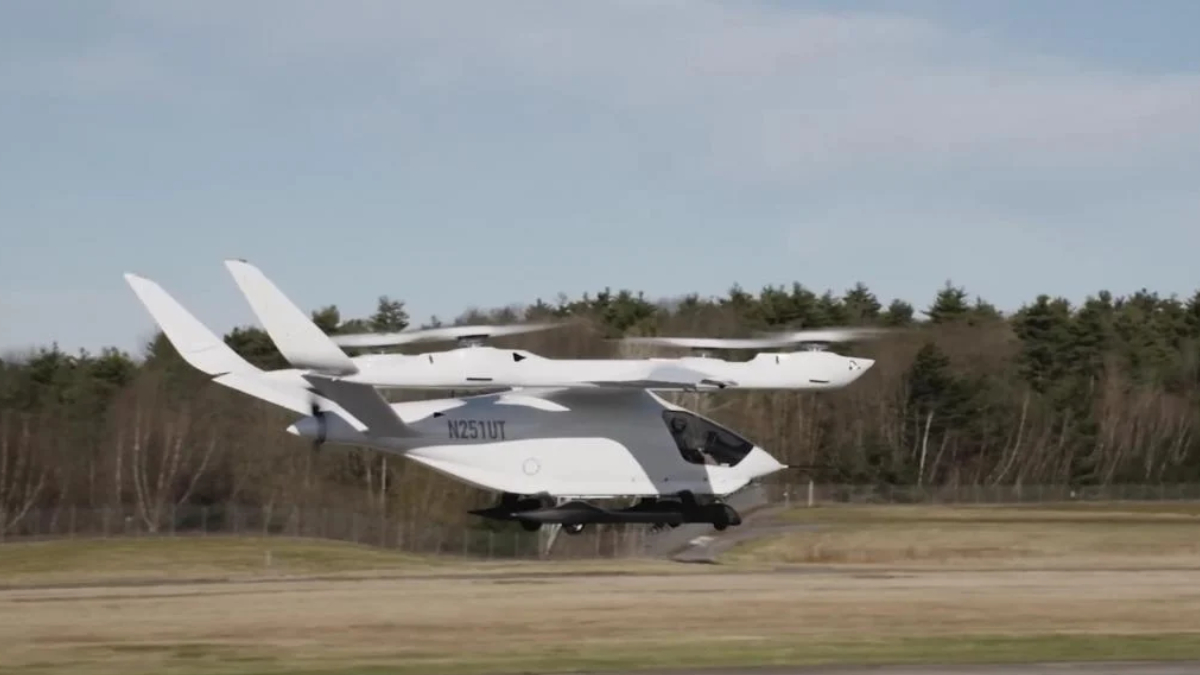 White tilt-rotor aircraft lifting off from a runway, with dual wing-mounted rotors and a compact cockpit.