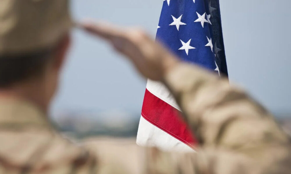 Soldier in uniform saluting the United States flag.