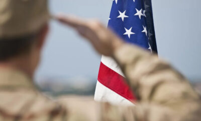 Soldier in uniform saluting the United States flag.