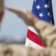Soldier in uniform saluting the United States flag.