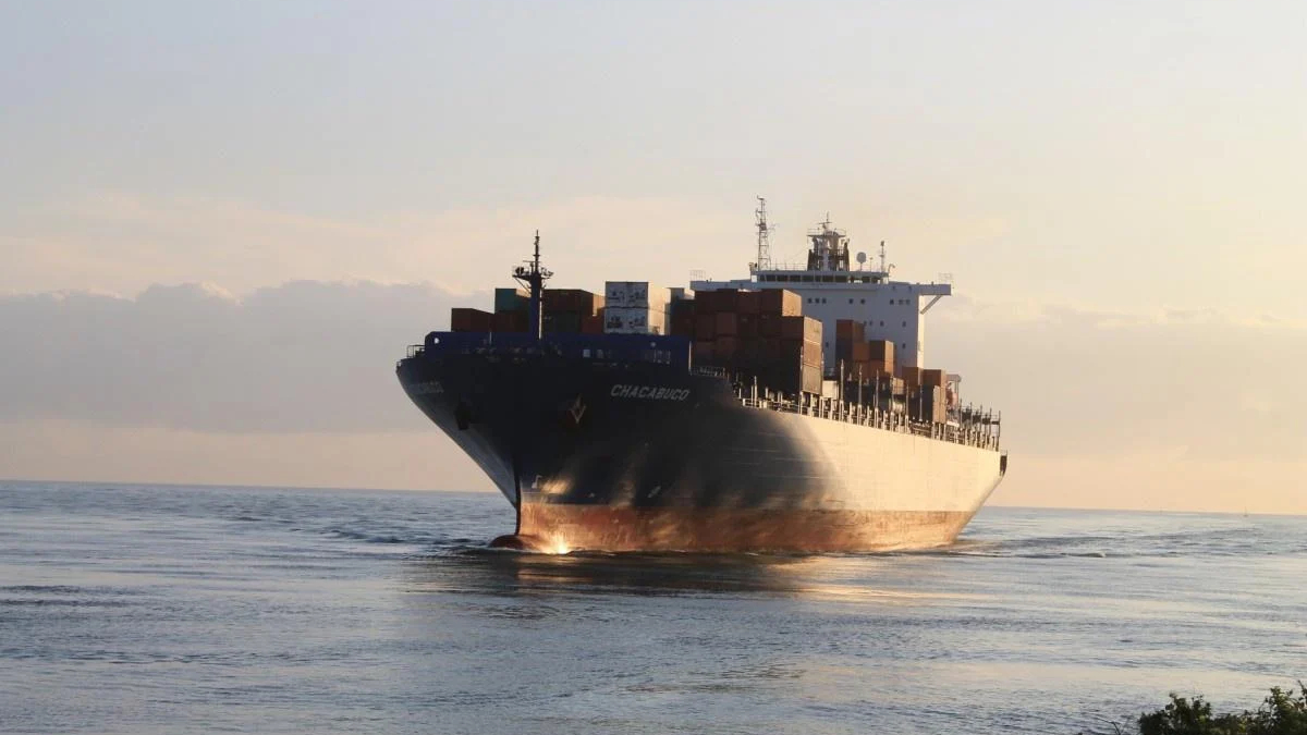 Container ship CHACABUCO at sea with stacked cargo containers under sunset light
