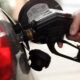 Close-up of a person pumping gas into a car at a fuel pump.