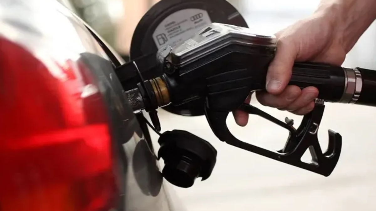 Close-up of a person pumping gas into a car at a fuel pump.