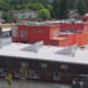 Orange, multi-story building under construction beside a dark brown low-rise, with a red construction crane nearby.