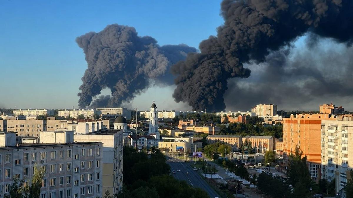 City skyline with huge black smoke plumes rising from distant fires near a church steeple
