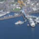 Aerial view of a marina with numerous sailboats docked at piers and a large ferry terminal along the waterfront.