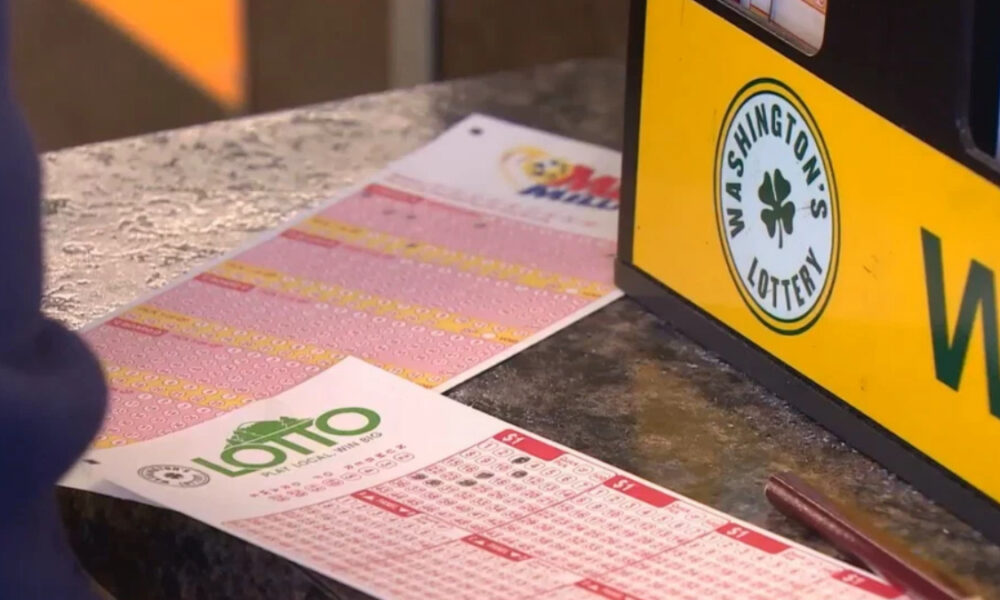 Close-up of pink and white lottery tickets laid out on a dark countertop beside a yellow lottery sign.