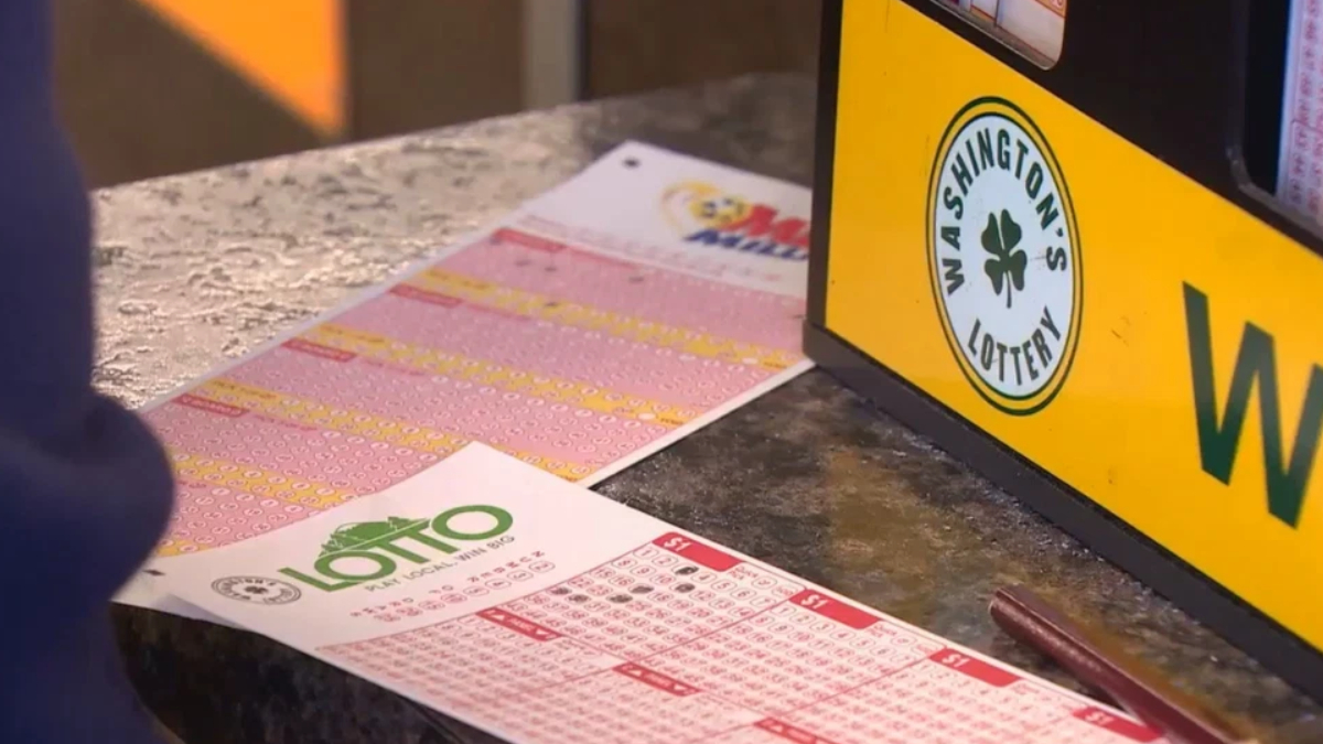 Close-up of pink and white lottery tickets laid out on a dark countertop beside a yellow lottery sign.