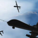 Three dark aircraft silhouettes fly in formation against a bright blue sky, viewed from below.