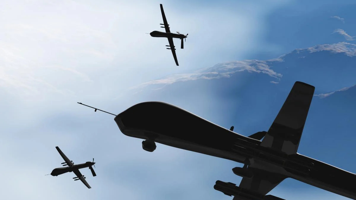 Three dark aircraft silhouettes fly in formation against a bright blue sky, viewed from below.